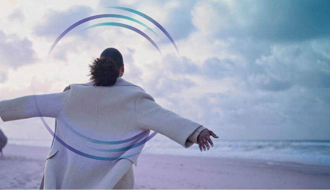 Person standing freely on a beach, representing the relief of reducing debt and reclaiming control of your financial future.