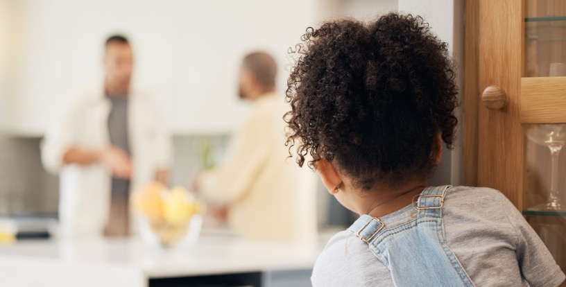 Child observing adults at home, illustrating how money scripts – invisible ink – can be learned through everyday family conversations and financial behaviour.