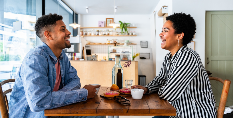 Two people seated at a café table engaged in conversation over coffee, illustrating the value of discussing financial decisions and life transitions with a trusted adviser.