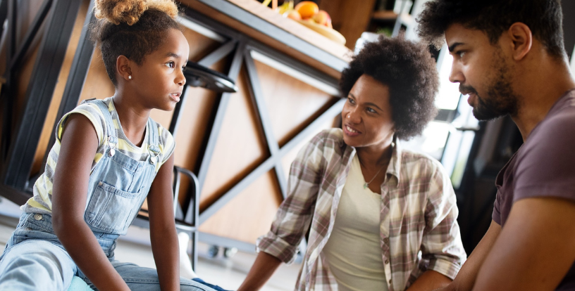 Family members sitting together and talking about money at home, illustrating open communication, shared values and financial conversations across generations.