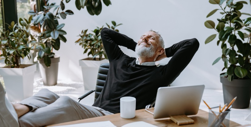 Relaxed man leaning back at his desk, illustrating how the Rule of 72 and compounding allow time to do more of the work.