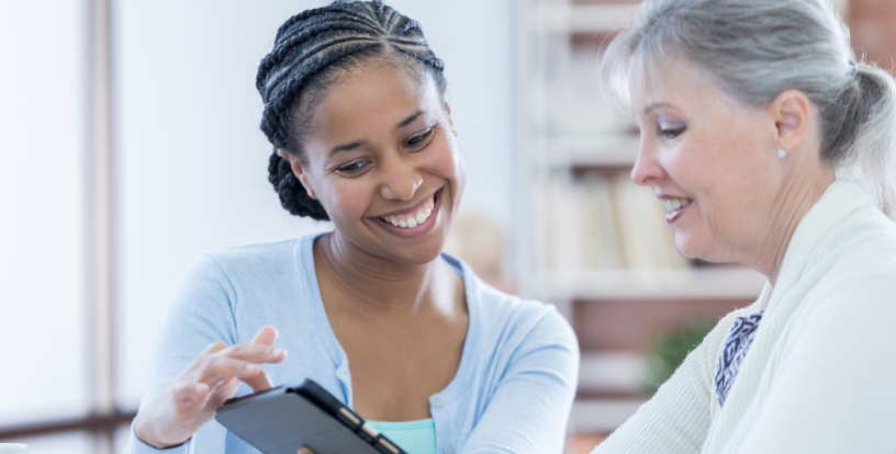 Two people reviewing information on a tablet while discussing future plans, illustrating purpose, fulfilment and meaningful life planning beyond retirement.