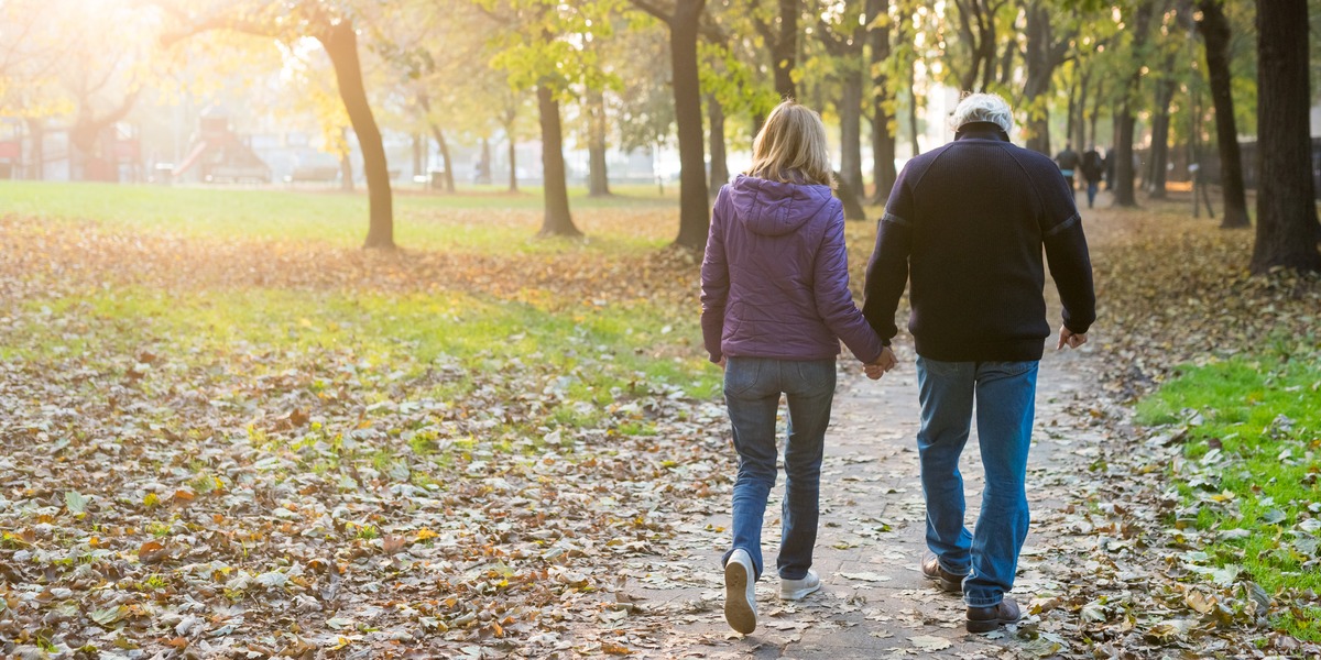 Two people walking together along a sunlit park path, symbolising financial resilience, adaptability and the ability to navigate life's challenges with confidence and long-term perspective.